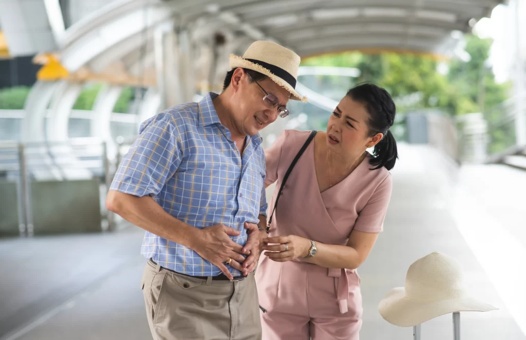 traveling man holding his stomach in pain from food poising with wife next to him