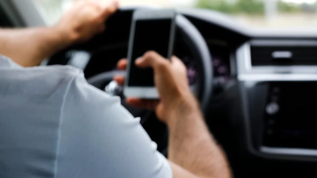 a distracted person holding a phone while driving
