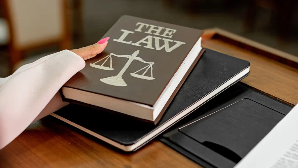 a hand of a car accident lawyer holding a book on top of a stack of books
