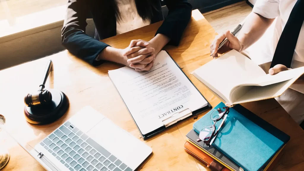 a woman and an attorney sitting at a table with a book and a pen