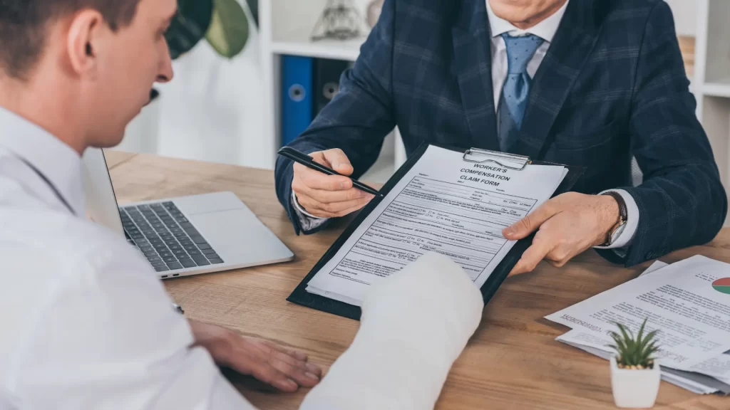 a man in a cast and an attorney holding a pen over a clipboard